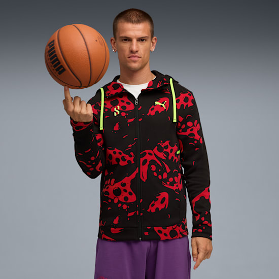 Against grey, a model spins a basketball on one finger, wearing a patterned hooded jacket.