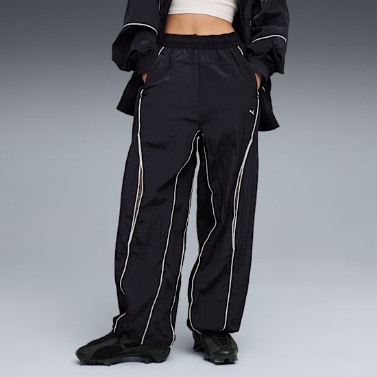 Sur fond gris, un mannequin porte un pantalon de survêtement noir et des baskets.