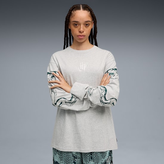 Modelka ze skrzyżowanymi rękami na szarym tle, w topie z motywem węża i wzorzystych spodniach.