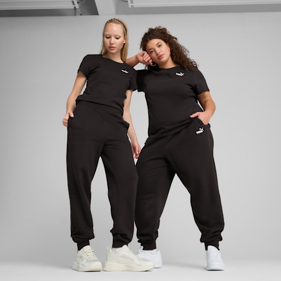 Two models pose against grey, wearing matching black t-shirts, joggers and trainers.