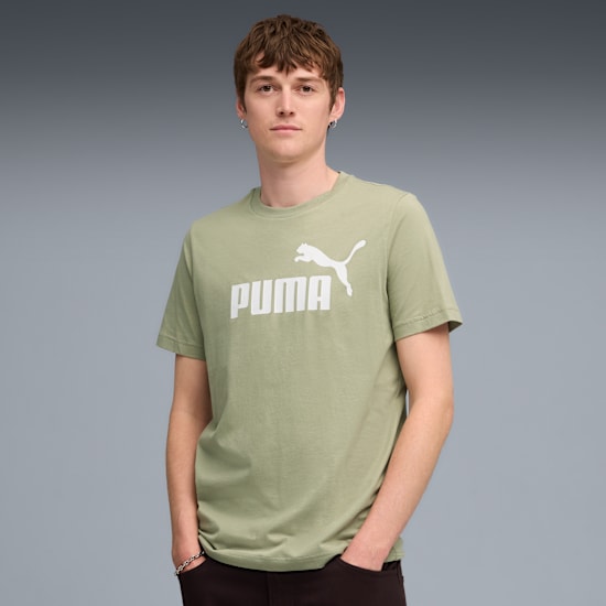 Een model poseert tegen een grijze achtergrond, gekleed in een olijfkleurig T-shirt met Puma-logo.
