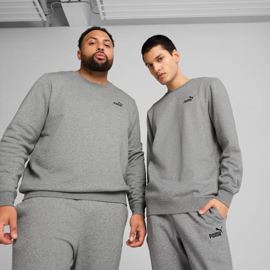 Zwei Models posieren vor grauem Hintergrund und tragen passende graue Sweatshirts und Trainingsanzüge.
