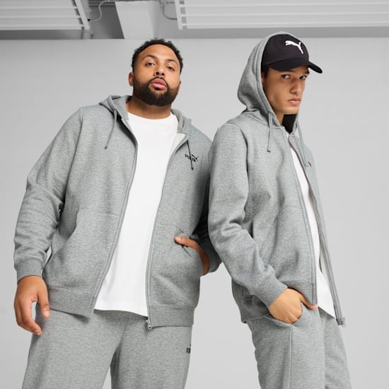 Zwei Models posieren vor grauem Hintergrund in grauen Kapuzenanzügen und Mützen.