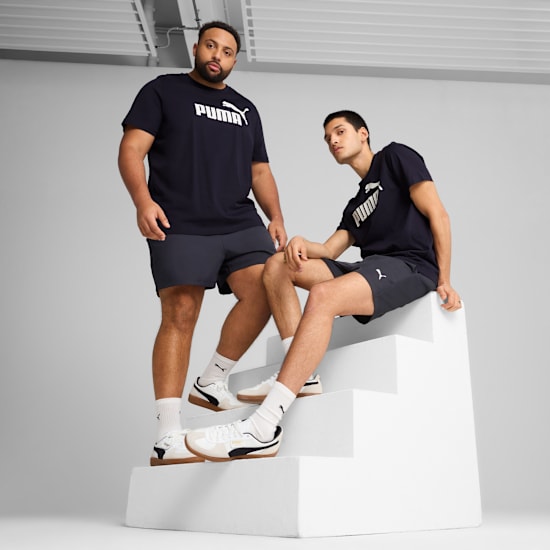 Two models pose on white steps against a grey backdrop, wearing Puma shirts and shorts.
