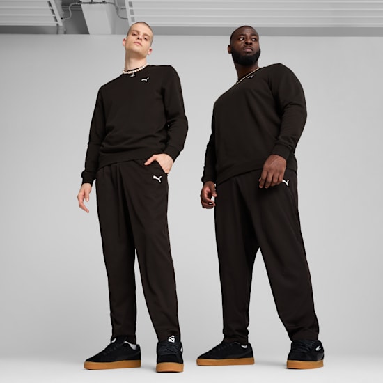 Two models pose on a grey background wearing black tracksuits and trainers.