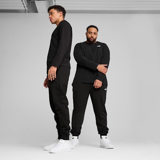 Deux modèles posent sur fond gris, portant des hauts à manches longues noirs, des pantalons et des baskets blanches.