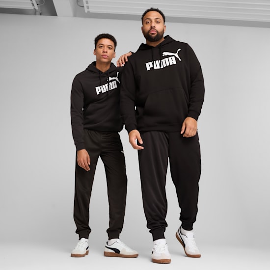 Deux modèles posent sur fond gris, portant des sweats à capuche, des pantalons de survêtement et des baskets Puma noirs.