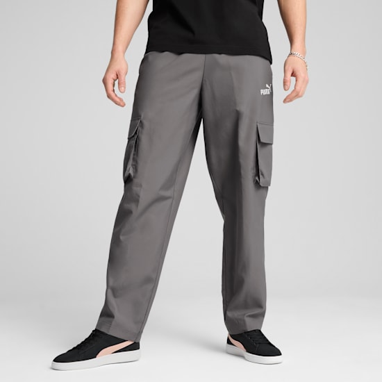 A model poses on a grey background wearing grey cargo trousers, a black t-shirt and black trainers.