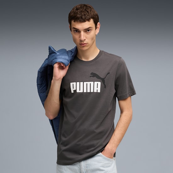 A model poses against grey, wearing a Puma t-shirt and holding a blue jacket.