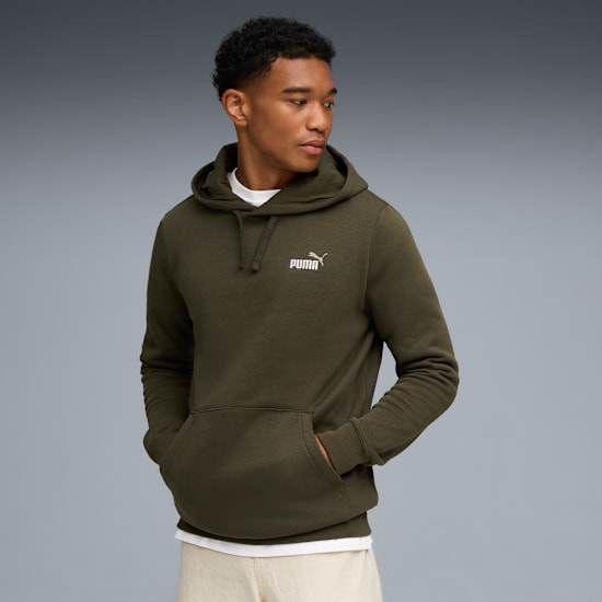 Sur fond gris, un mannequin pose avec un sweat à capuche vert, un t-shirt blanc et un pantalon beige.