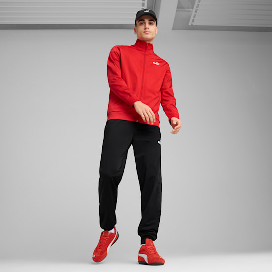 A model poses on grey wearing a red jacket, black trousers, cap and red trainers.