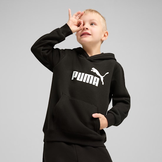 Un enfant pose sur fond gris, portant un sweat à capuche Puma noir, faisant un geste 'OK'.
