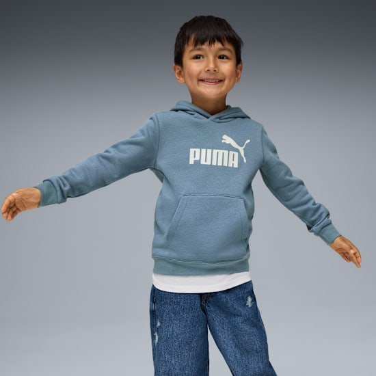 Un enfant souriant, bras ouverts, porte un sweat à capuche bleu avec logo blanc sur fond gris.