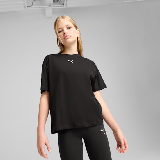 Ein Model vor grauem Hintergrund, mit schwarzem T-Shirt und schwarzen Leggings.