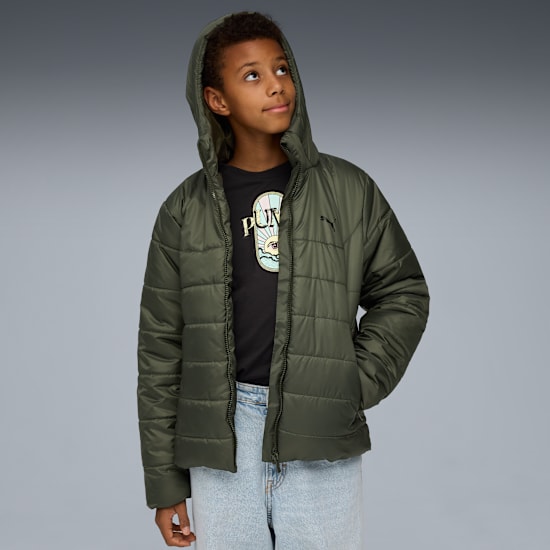 Een model kijkt omhoog tegen een grijze achtergrond, gekleed in jas, T-shirt en jeans.