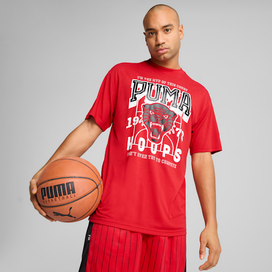 A model holds a basketball, wearing a red Puma graphic tee and shorts against grey.