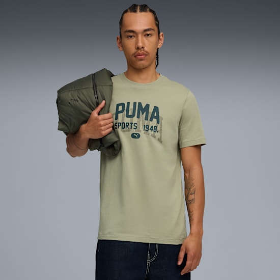 A model stands against a grey background, wearing a Puma t-shirt and holding a jacket.
