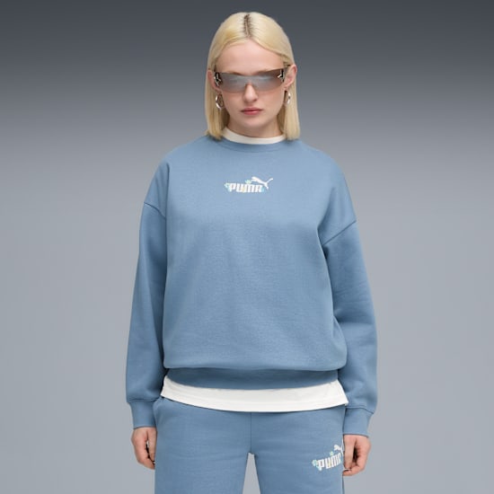 Un mannequin avec des lunettes de soleil pose sur un fond gris, portant un sweat-shirt Puma bleu et un survêtement assorti.