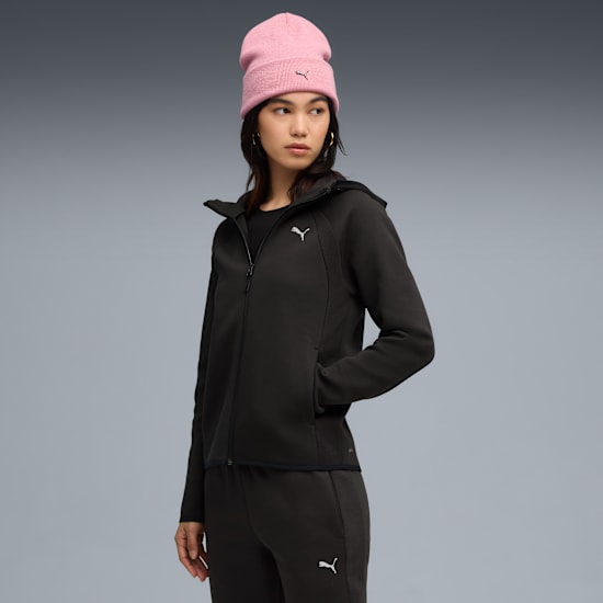 A model poses against grey backdrop wearing a black tracksuit and pink beanie.