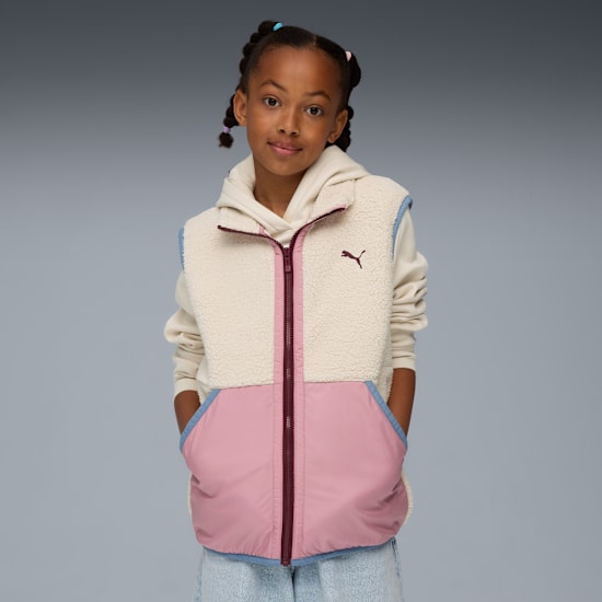 Tegen grijs draagt een model een crème-roze bodywarmer over een hoodie.