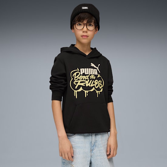 A model stands against a grey background wearing a beanie, glasses, and a black Puma hoodie.