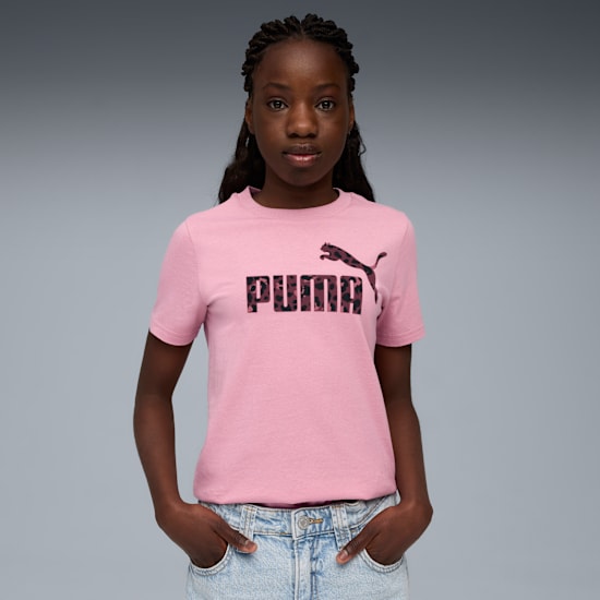 Against grey, a model poses, wearing a pink Puma t-shirt and light blue jeans.
