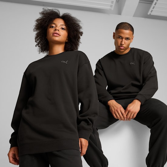 Two models pose against a grey backdrop, wearing matching black sweatshirts and trousers.