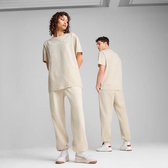 Twee modellen poseren tegen een grijze achtergrond, gekleed in bijpassende crèmekleurige outfits en sneakers.