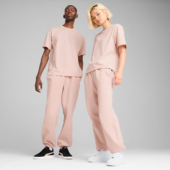 Two models pose in matching pink outfits against a grey backdrop.