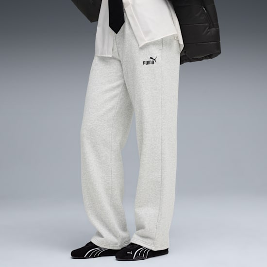 Against grey, model wears grey trousers, black shoes, white shirt and black jacket.