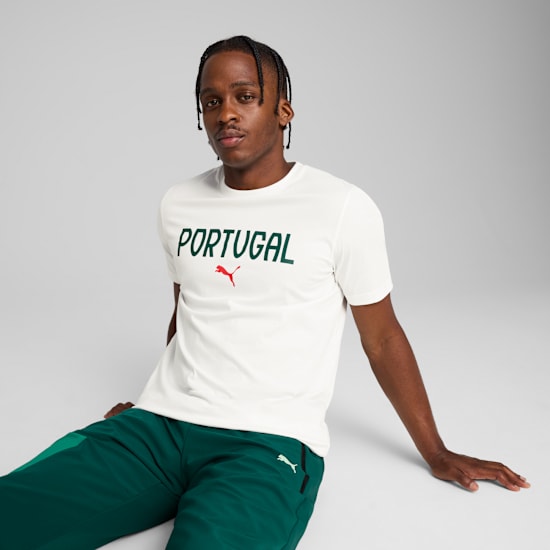 Een model poseert tegen een grijze achtergrond in een wit 'Portugal' T-shirt en groene broek.
