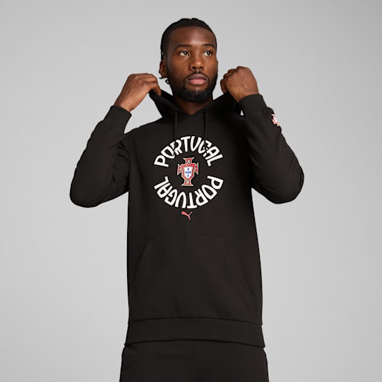 Vor grauem Hintergrund justiert ein Model einen schwarzen Hoodie mit Portugal-Grafik.