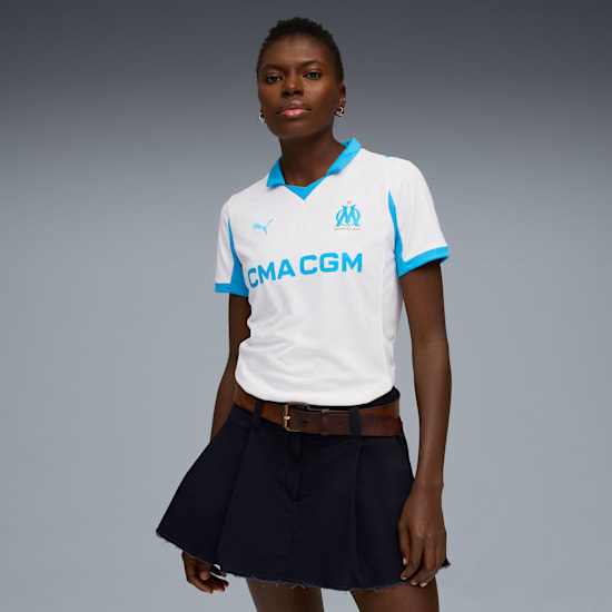 A model poses against grey, wearing a white and blue shirt with a navy skirt.
