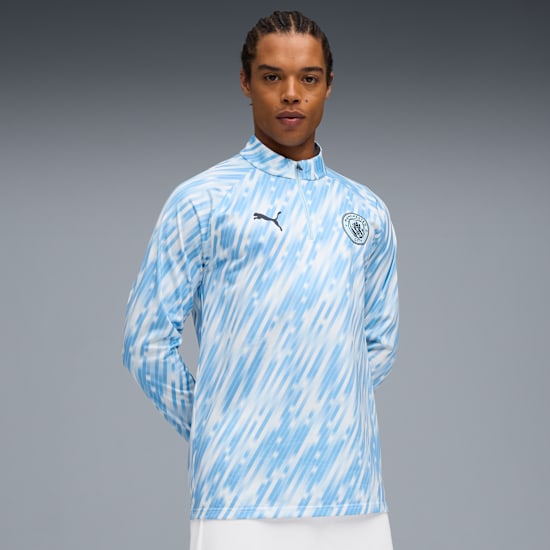 A model stands against a grey backdrop, wearing a patterned light blue and white top.