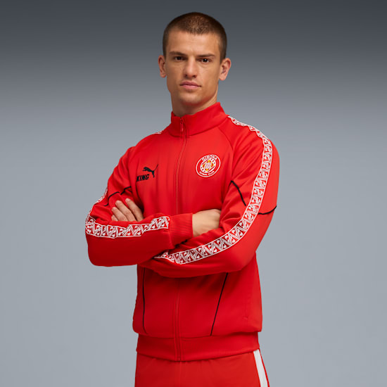 A model with crossed arms wears a red jacket against a grey backdrop.