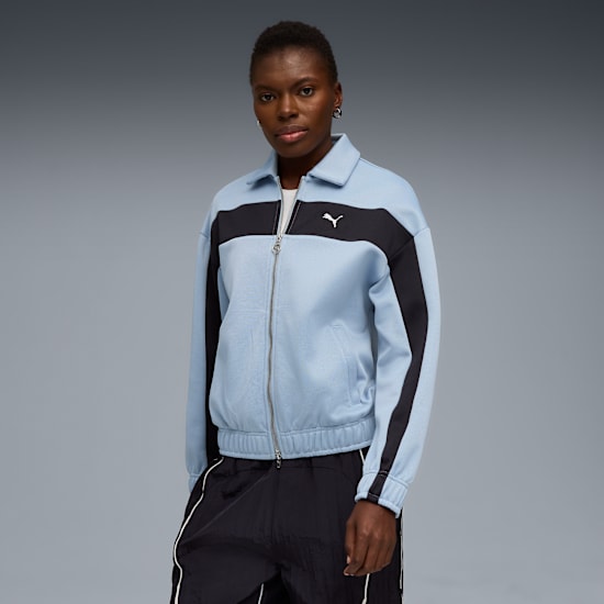 Un mannequin pose sur fond gris, portant une veste zippée bleu clair et noire.