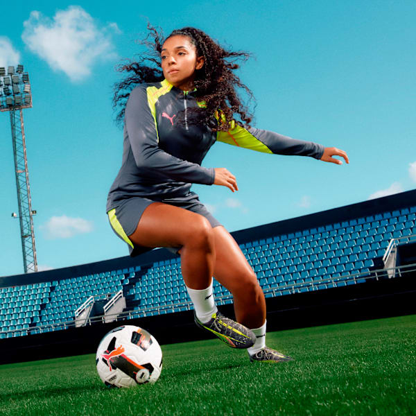Grey PUMA training set women's with neon accents, worn by a woman playing football.