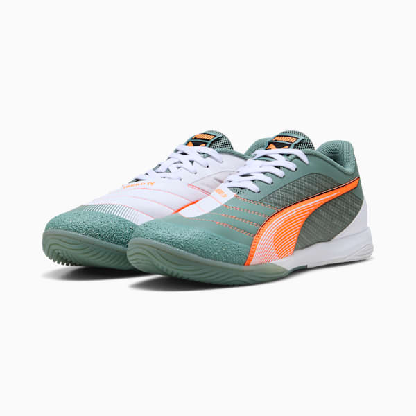 Two PUMA trainers, one white with orange, one green with orange stripes, for adults.