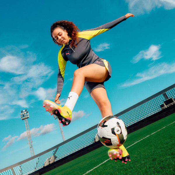 Yellow PUMA football boots for adults, with black detailing and pink studs.