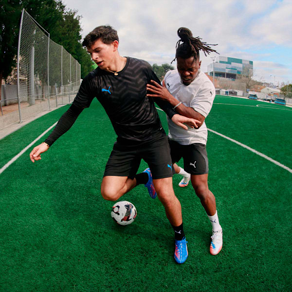 Black PUMA men's training kit with blue logo, worn during a football match.