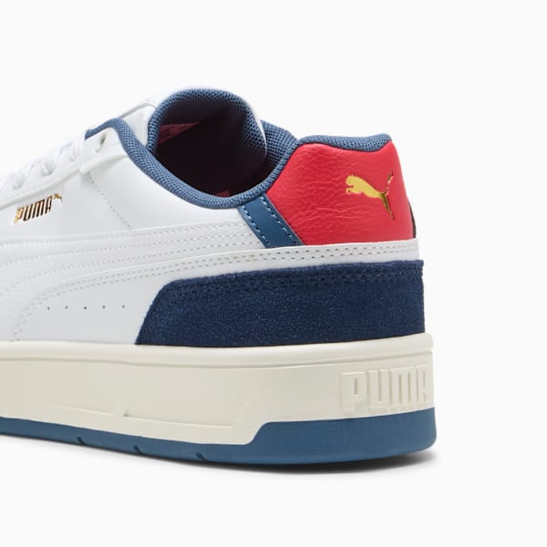 White PUMA trainers with blue suede, red heel and gold logo detail.