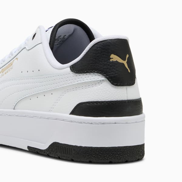 White PUMA trainer, with black accents and gold logo detail on the heel.