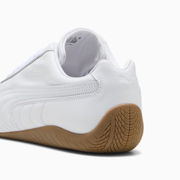 White PUMA unisex shoe with a brown textured sole, shown from a rear angle.