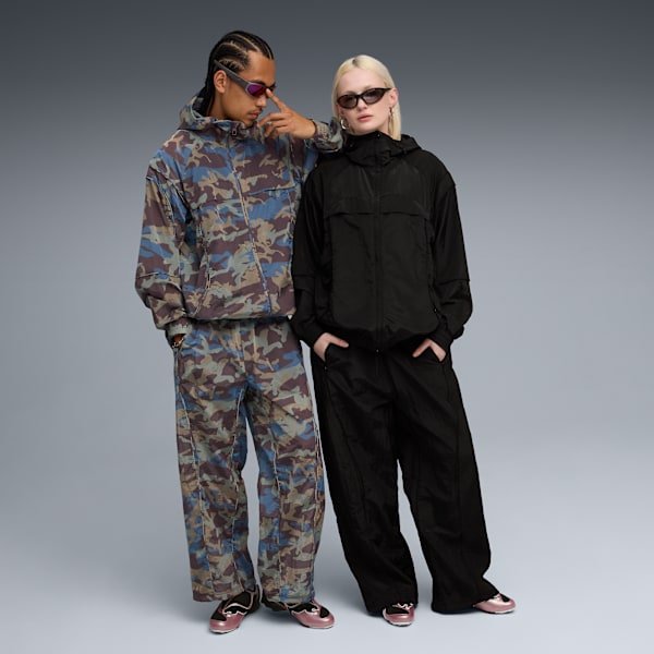 Two models pose against grey backdrop, wearing jackets and trousers with sunglasses.