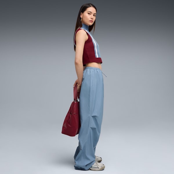 A model poses against a grey backdrop, wearing a colour-blocked top and baggy blue trousers.