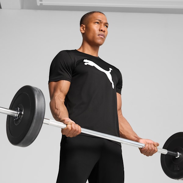 Against a grey backdrop, a model lifts a barbell wearing a black Puma t-shirt and trousers.