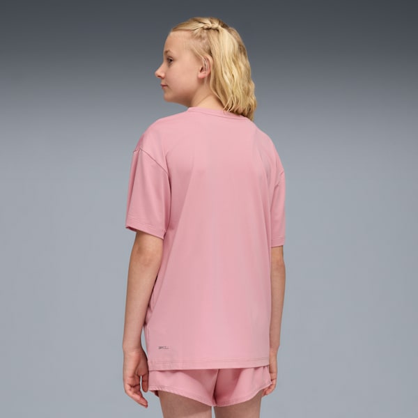 Against grey, a child model wears a pink t-shirt and shorts, looking to the side.
