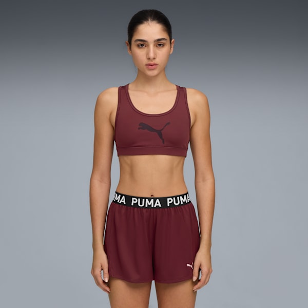 Model in a maroon sports bra and shorts with a Puma logo against a grey backdrop.