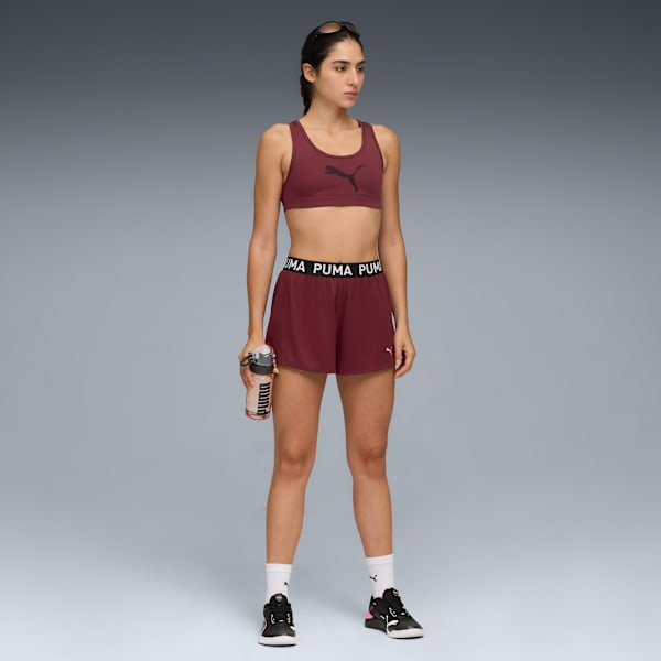 On grey, a model poses in maroon activewear with a branded water bottle.