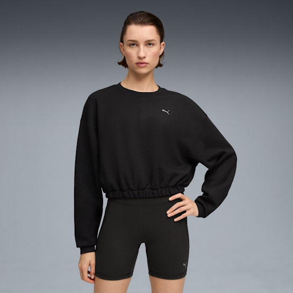 A model poses against a grey backdrop wearing a black sweatshirt and cycling shorts.